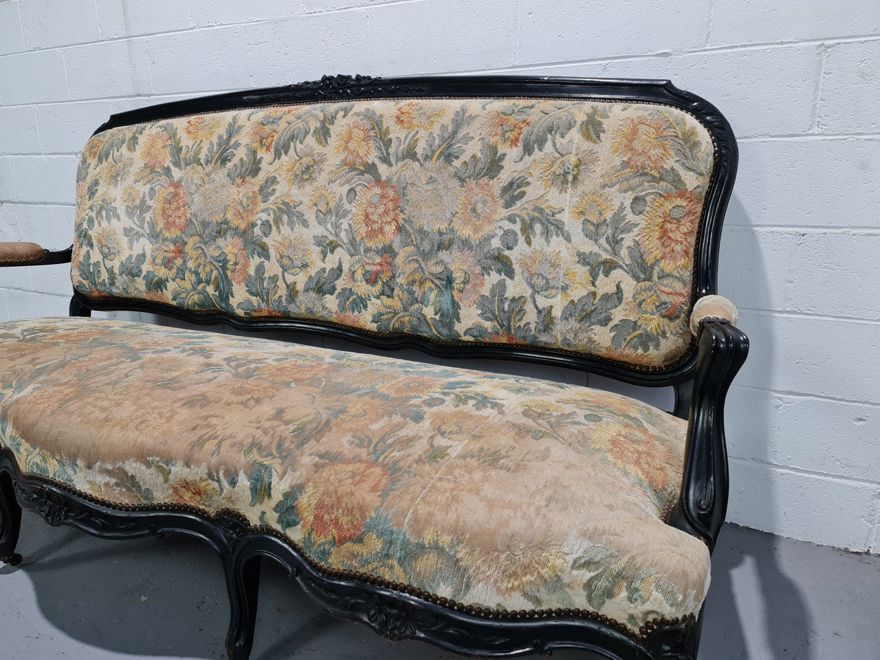 A Substantial Antique 19th Century Louis XV style ebonized serpentine front settee. The fabric is in used condition showing use and could be used as is or reupholster.
