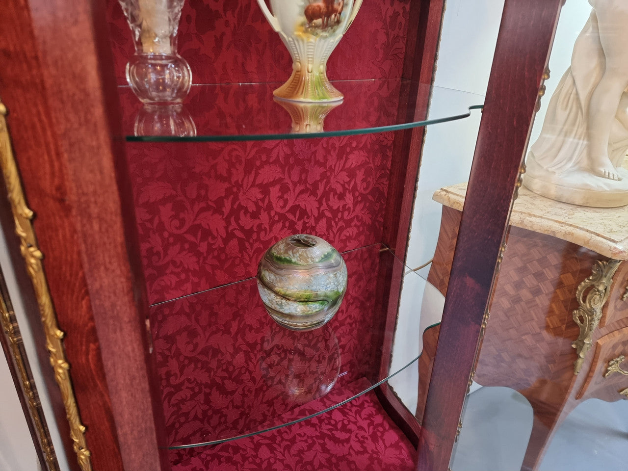 French Mahogany two shelf vitrine with curved glass and brass mounts. It has a lovely frabic interior and two glass shelves. In good original detailed condition.