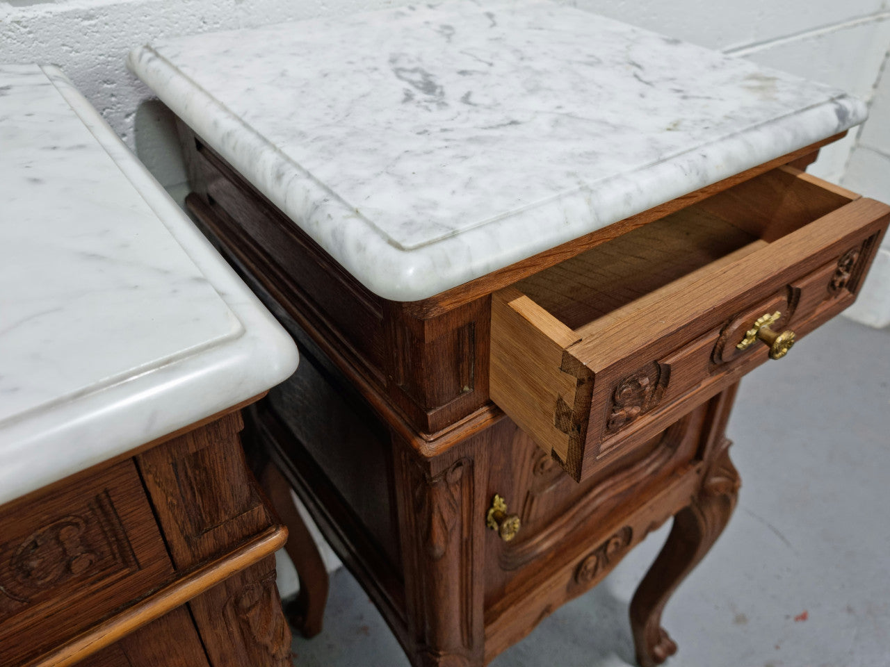Lovely pair of French Oak carved Louis XV style bedside cabinets with a white marble top, drawer and cupboard in good original detailed condition.
