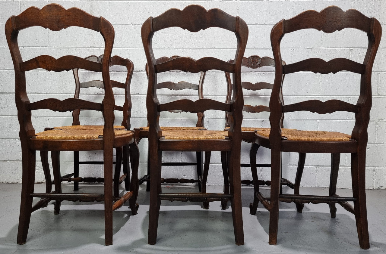 Set of six French dark Oak rush seat dining chairs with ladder back. They are in good detailed original condition and very comfortable to sit in.