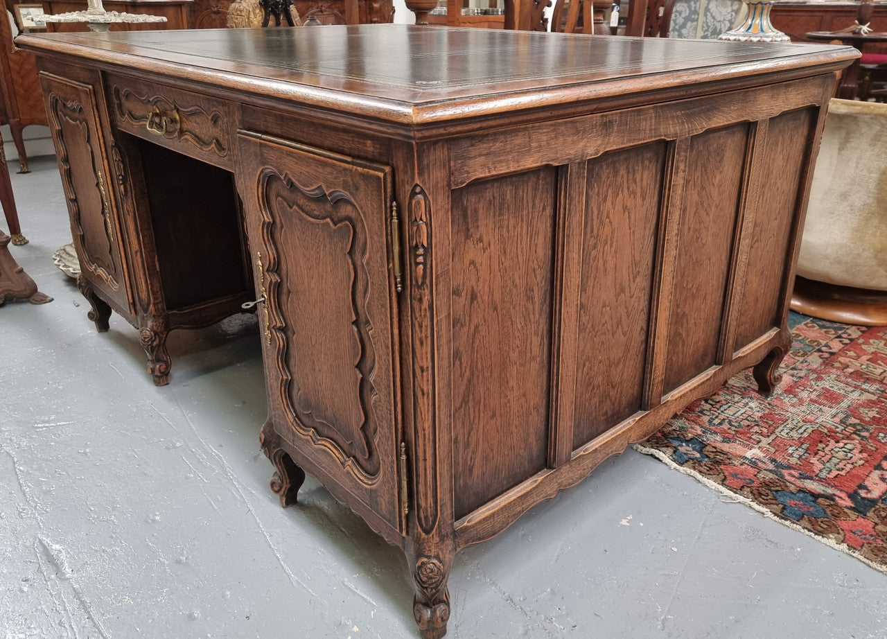 Fabulous Louis XV style French Oak beautifully carved full partners desk with an amazing tooled leather top. Both sides have a functioning drawer in the middle and two cupboards either side. On both sides one cupboard door opens up to four smaller internal drawers. Plenty of storage space and a large top surface to work on. It is in good original detailed condition.
