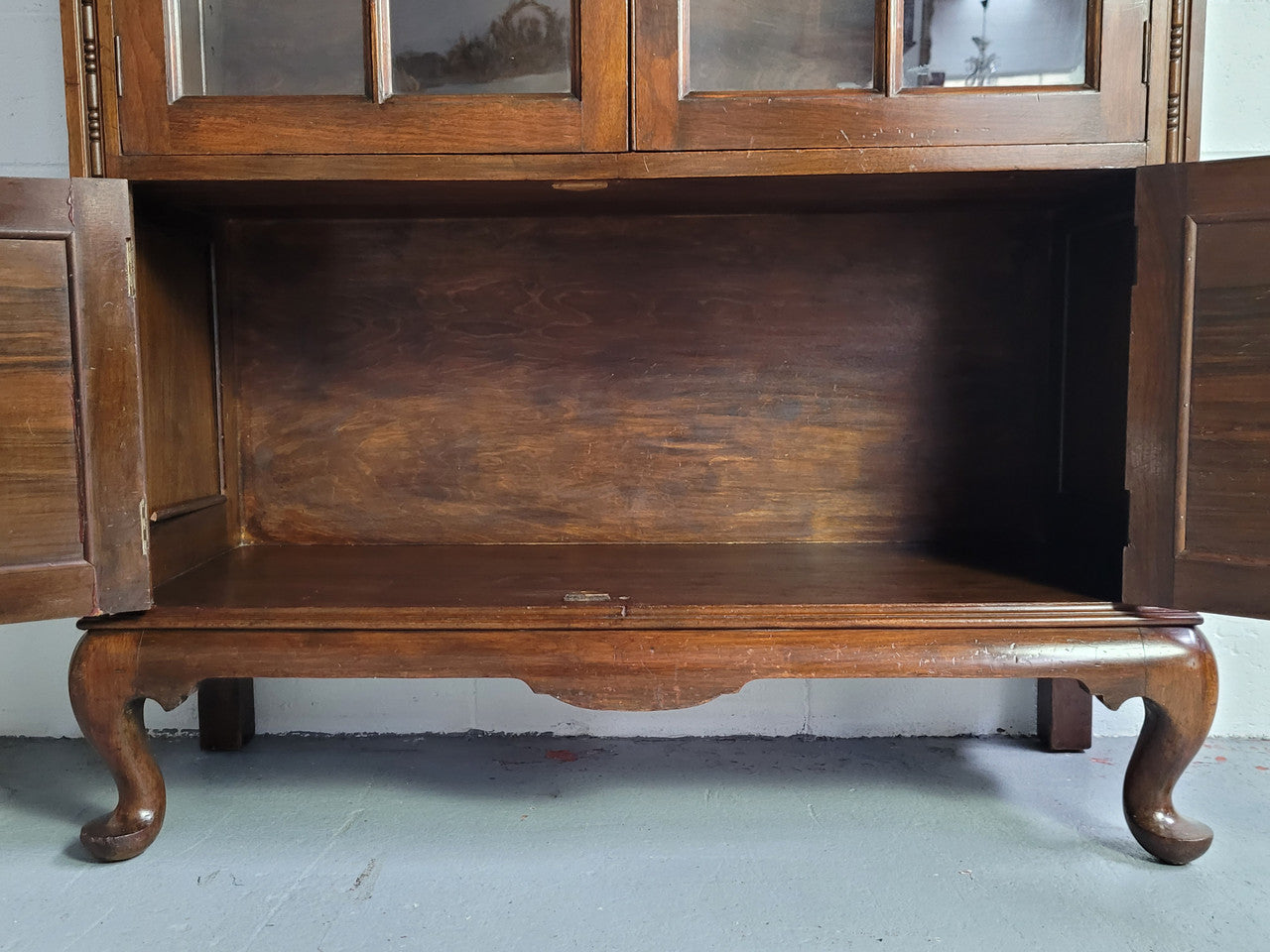 English Walnut two door bookcase with original glass. It has three adjustable shelves and hidden storage below behind two smaller doors. It is in food original condition.