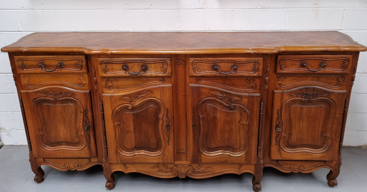 A Beautifully carved French Walnut Louis XV style four door sideboard. Plenty of storage space with four doors as well as four drawers. It is in good original detailed condition.