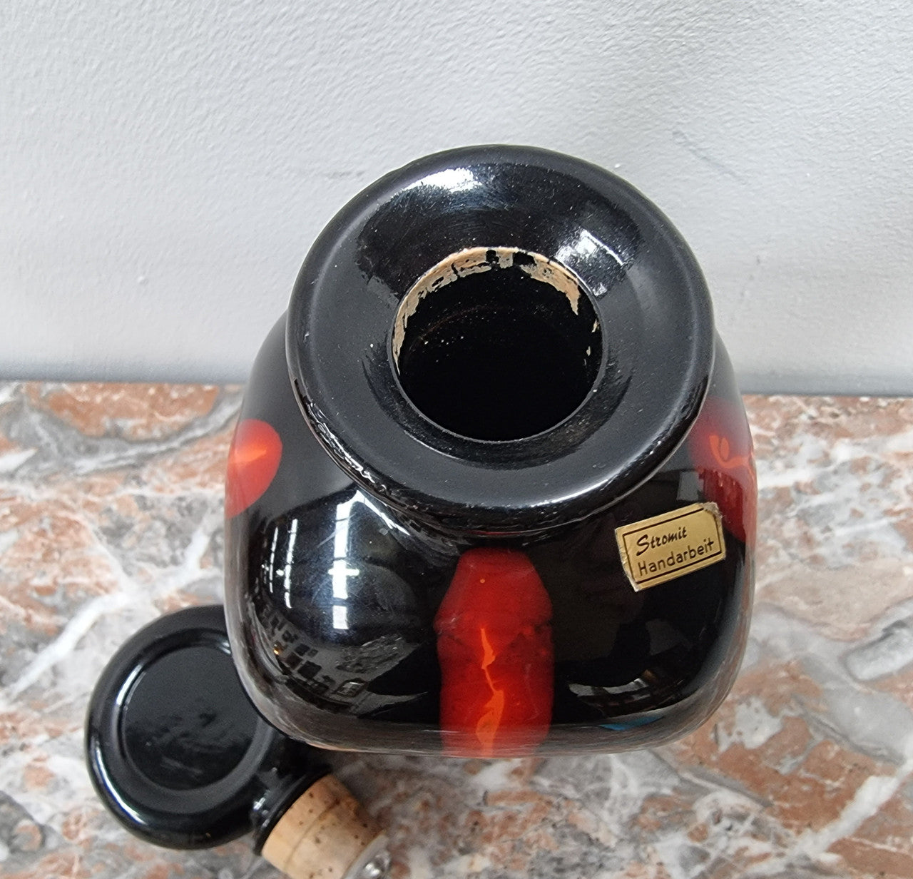 Vintage Designer glass carafe by “Stromit Handarbeit”. Dark background with flashes of orange/red.