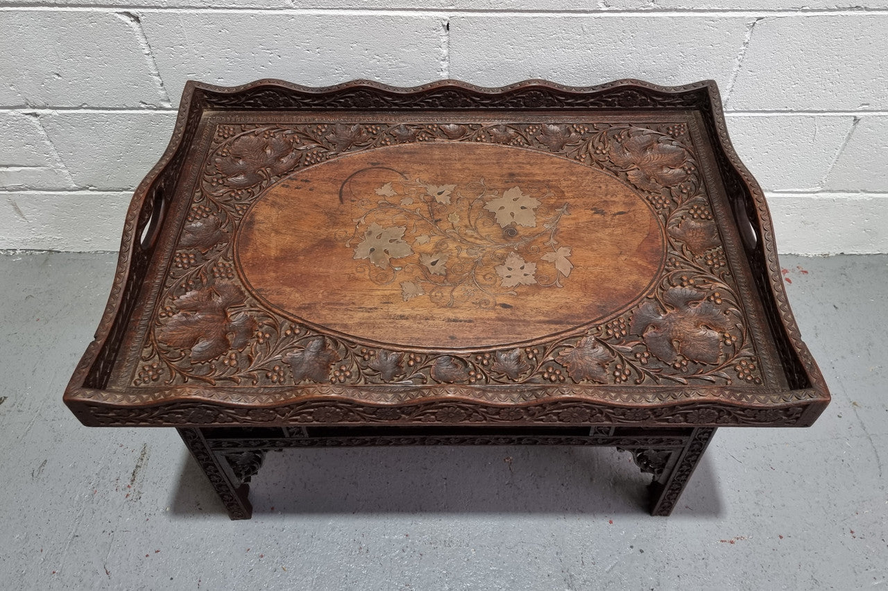 Anglo Indian folding occasional table with lift-up tray top. The tray has brass inlay and ornate carvings. The bottom of the table folds down and it is in good original condition.