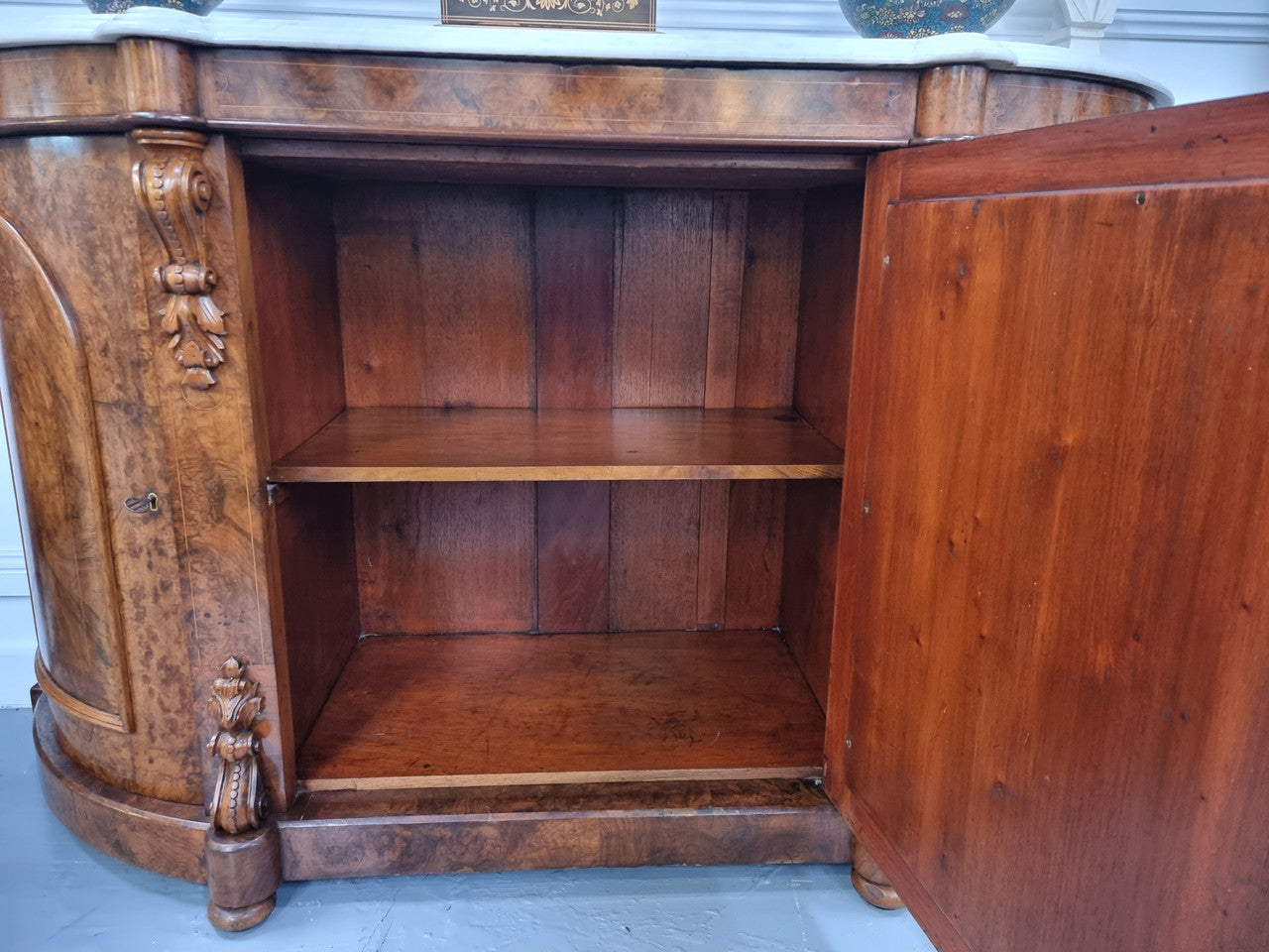 An elegant Antique Victorian Burr wood Walnut marble-top sideboard credenza with a mirrored center door. It has a white shaped marble top, mirror front, nicely carved details and three swing doors along with two keys. It is in good original detailed condition.