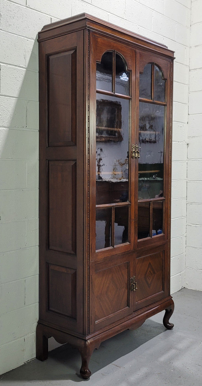 English Walnut two door bookcase with original glass. It has three adjustable shelves and hidden storage below behind two smaller doors. It is in food original condition.