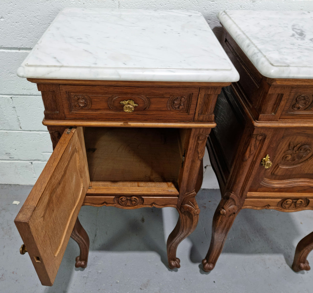 Lovely pair of French Oak carved Louis XV style bedside cabinets with a white marble top, drawer and cupboard in good original detailed condition.