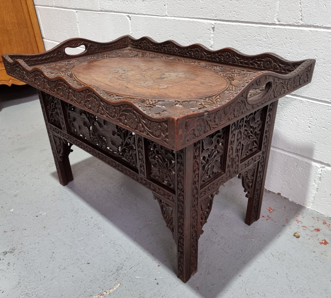 Anglo Indian folding occasional table with lift-up tray top. The tray has brass inlay and ornate carvings. The bottom of the table folds down and it is in good original condition.