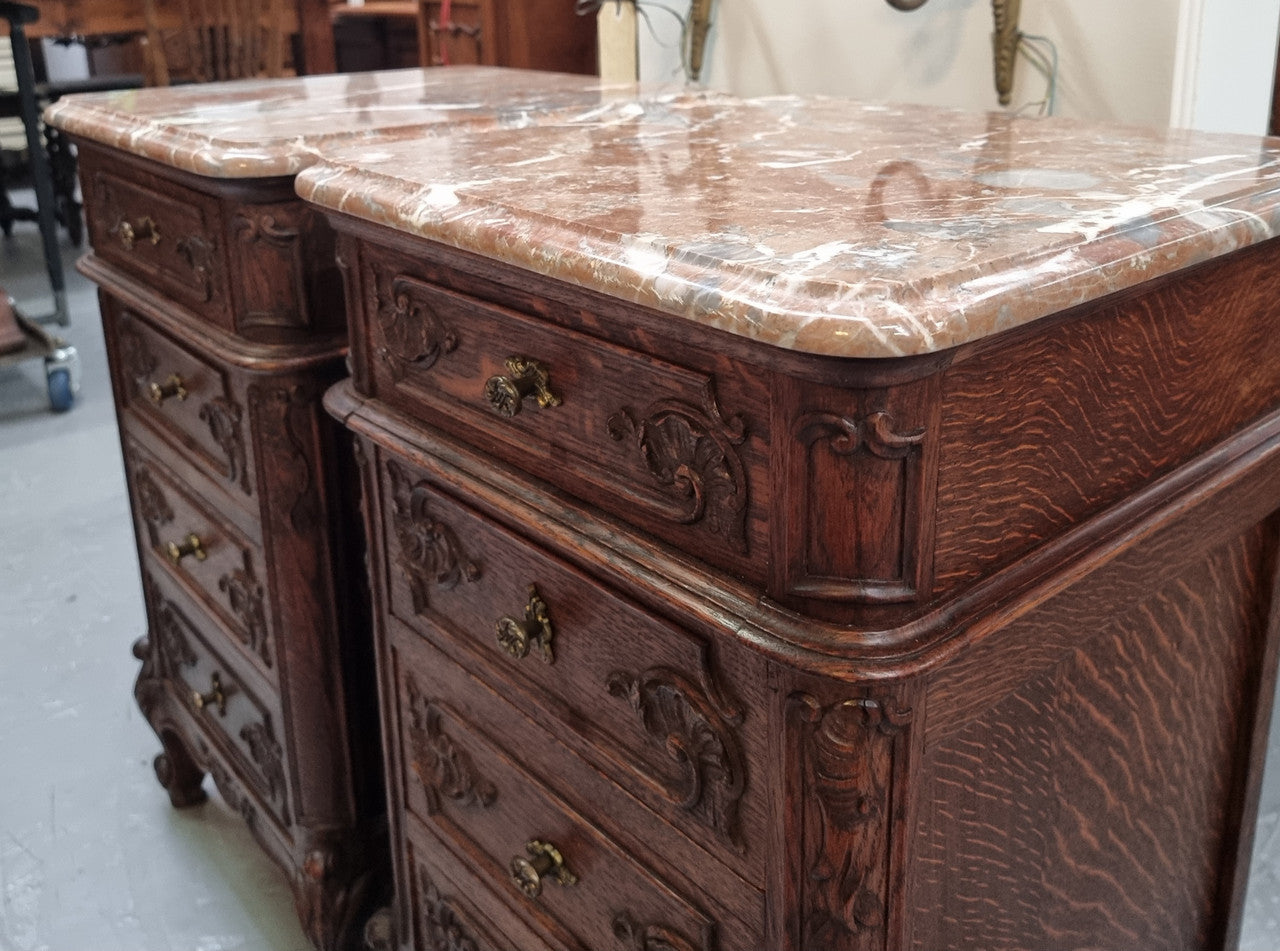 A pair of hard to find French Oak Louis XV style four drawer marble topped bedsides with attractive carvings. They are in good original detailed condition and have been sourced from France.