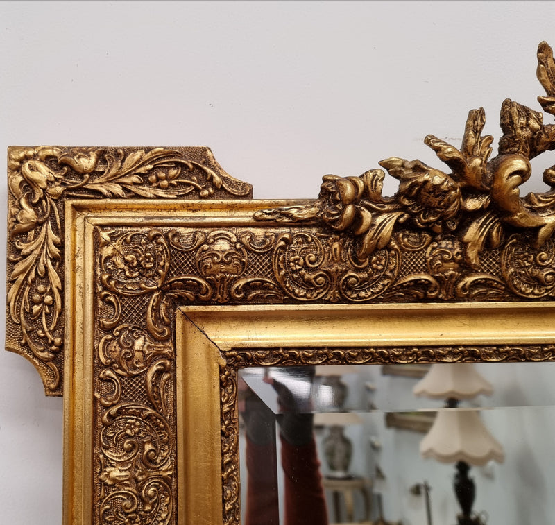 French ornate gilt decorated and floral bevelled mirror. It has been sourced from France and it is in good original condition.