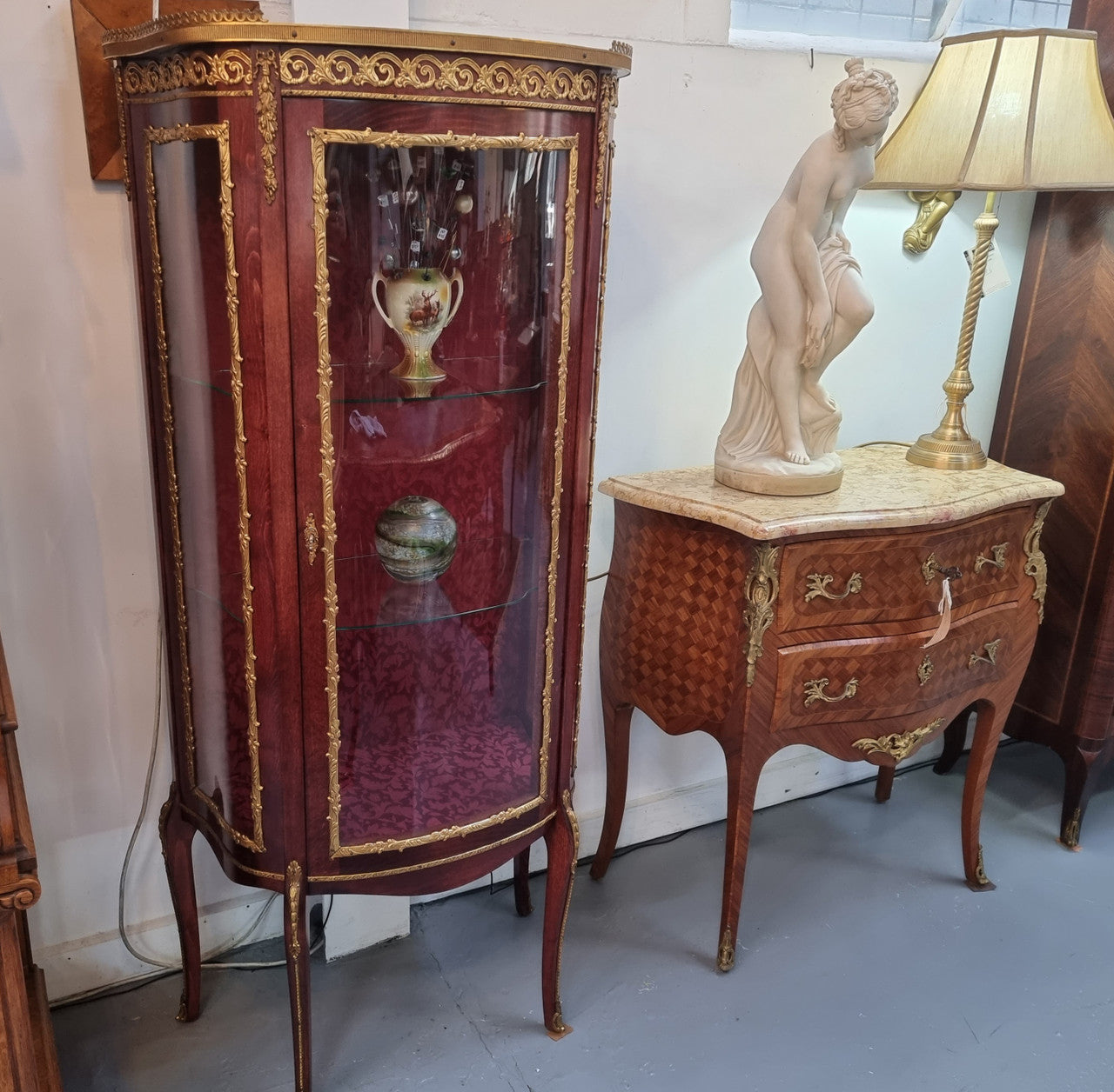 French Mahogany two shelf vitrine with curved glass and brass mounts. It has a lovely frabic interior and two glass shelves. In good original detailed condition.