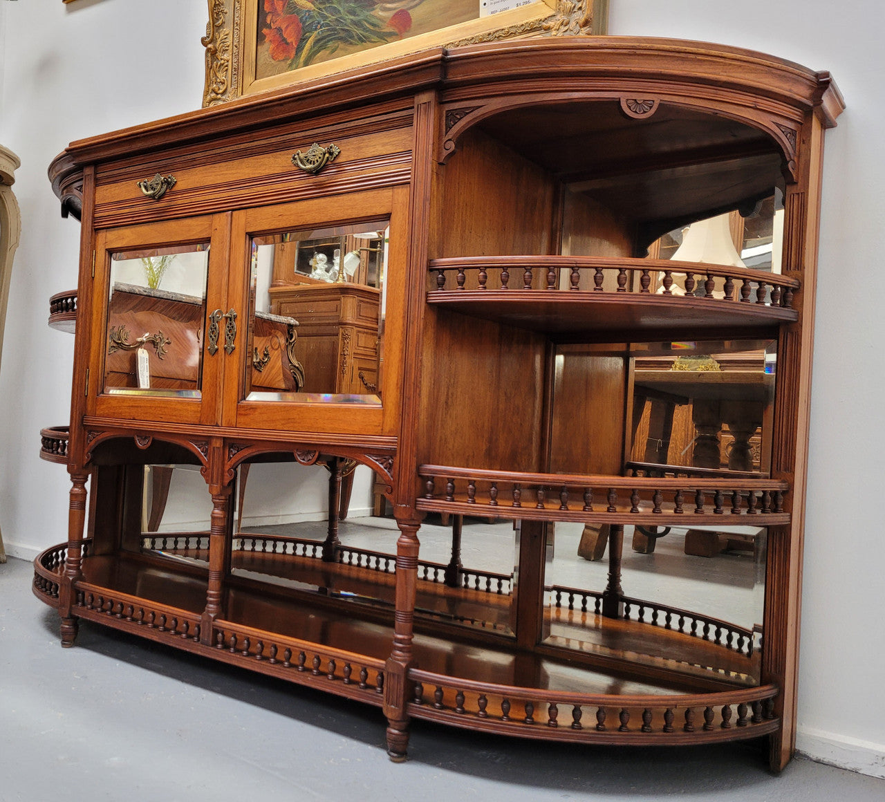 A high quality Antique Walnut sideboard featuring two mirrored doors, two drawers and five open shelf areas with mirror backing. It is in good original detailed condition.
