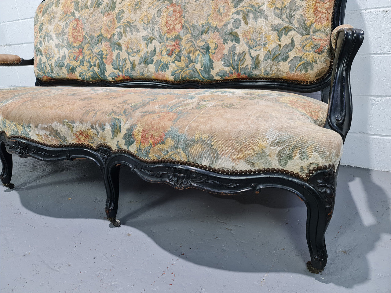 A Substantial Antique 19th Century Louis XV style ebonized serpentine front settee. The fabric is in used condition showing use and could be used as is or reupholster.