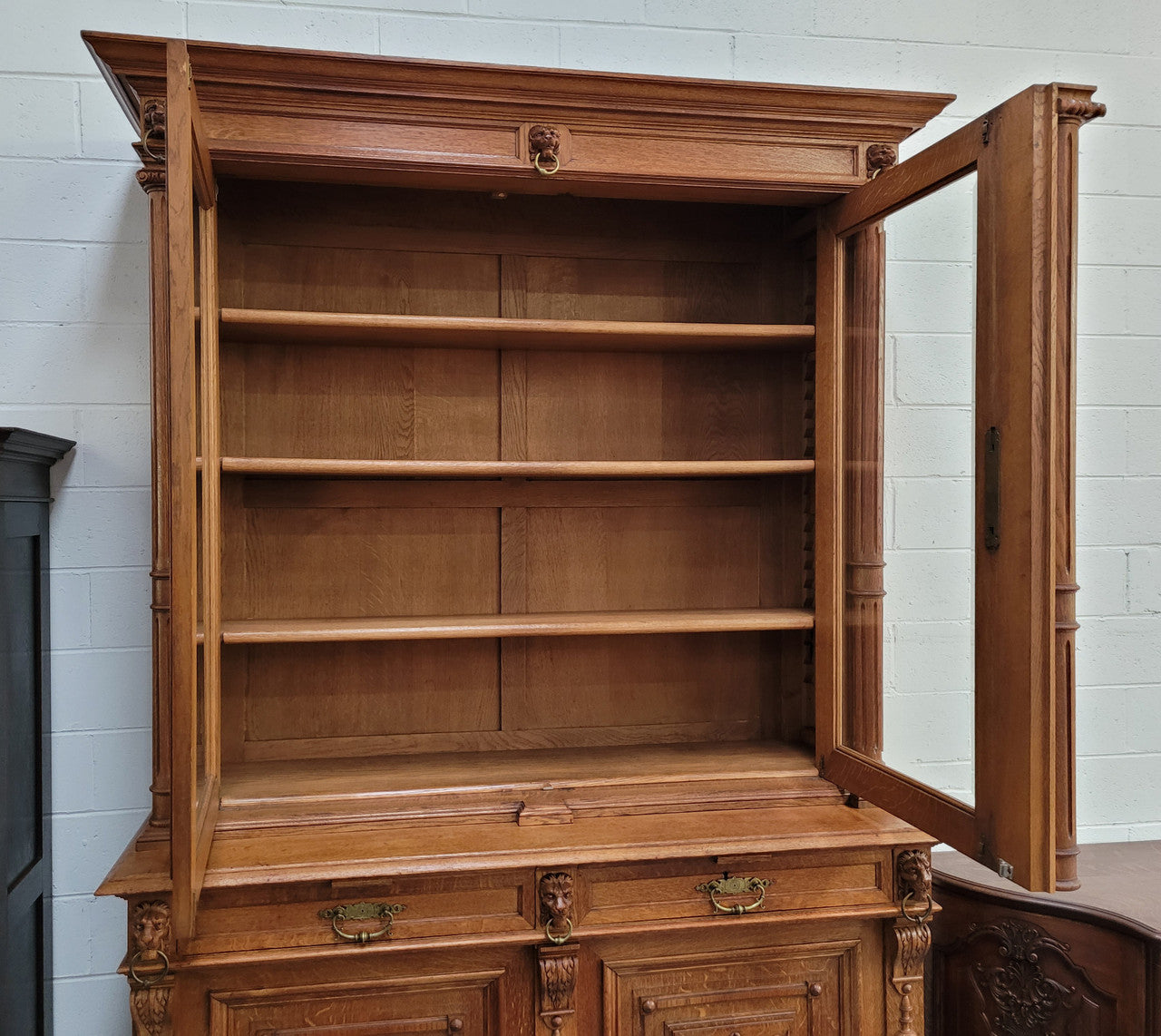 Amazing French 19th Century Oak two-door bookcase. Amazing detailed carvings throughout and plenty of storage space with three adjustable shelves at the top, two drawers, and a further shelf at the bottom. Also has two pull out reading slides giving you a large area to view your books on. In very good original detailed condition.
