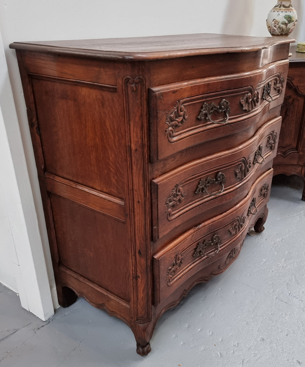 Antique French beautifully carved dark Oak commode with three drawers and ornate handles. It is in good original detailed condition.