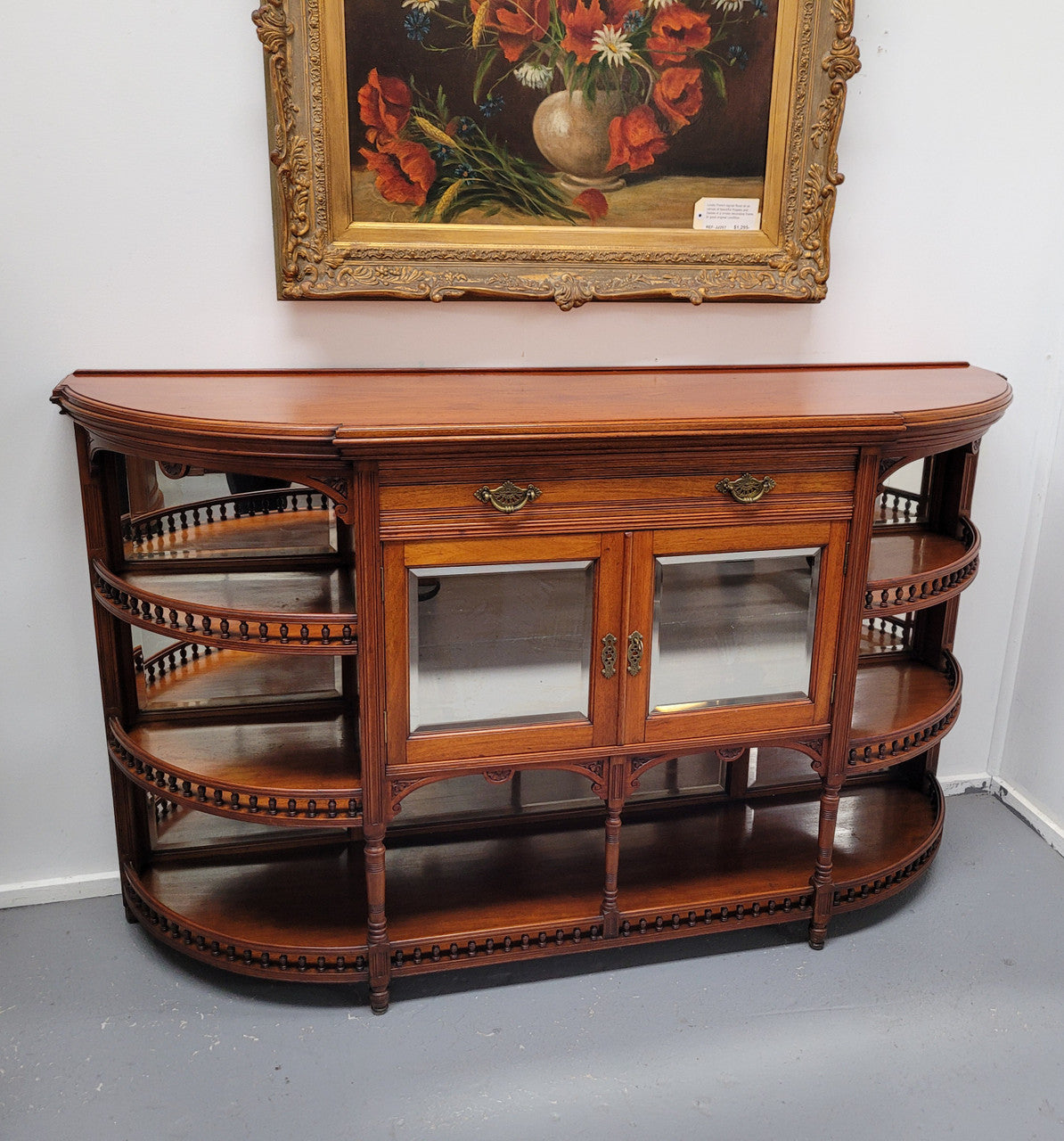 A high quality Antique Walnut sideboard featuring two mirrored doors, two drawers and five open shelf areas with mirror backing. It is in good original detailed condition.