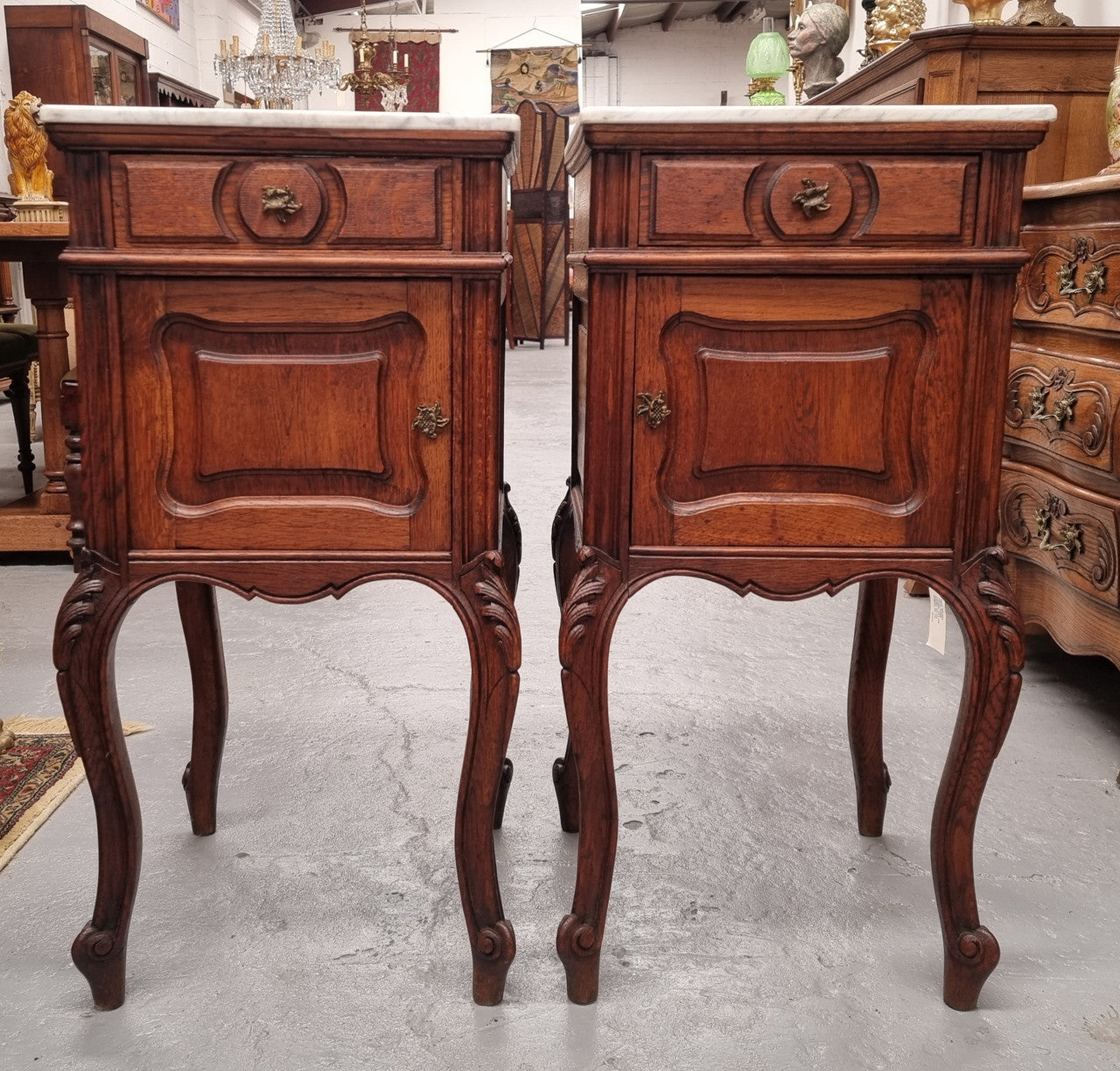 Elegant French Louis XV style pair of carved Oak white marble top bedsides. They are in good original condition and they have been detailed to a high standard. They have been sourced from France.