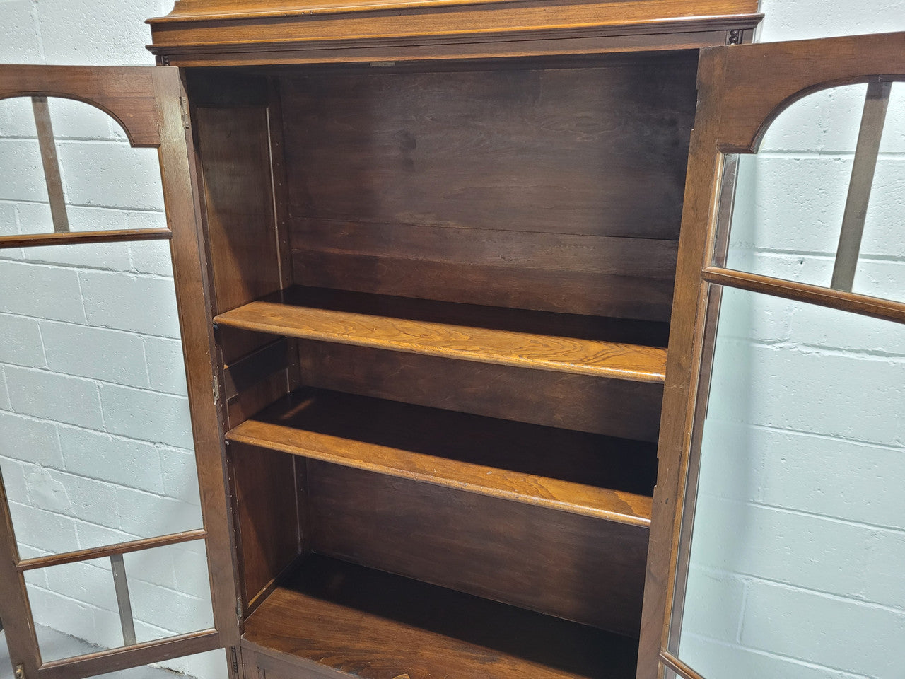 English Walnut two door bookcase with original glass. It has three adjustable shelves and hidden storage below behind two smaller doors. It is in food original condition.