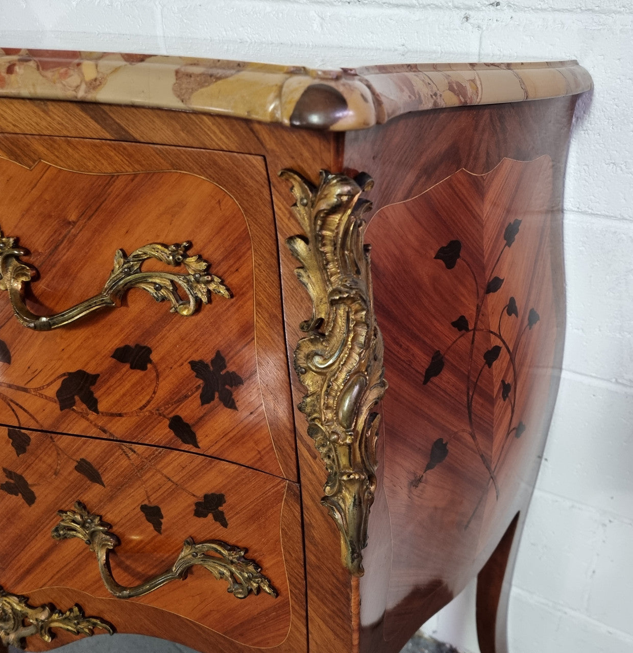 Charming petite French Louis XV style commode featuring two drawers, marquetry inlay, ormolu trim and marble Top. In good original detailed condition. Circa: 1930’s.