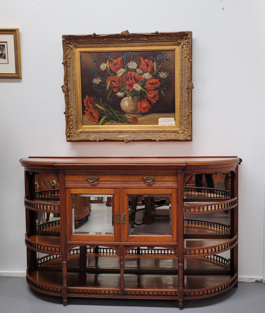 A high quality Antique Walnut sideboard featuring two mirrored doors, two drawers and five open shelf areas with mirror backing. It is in good original detailed condition.
