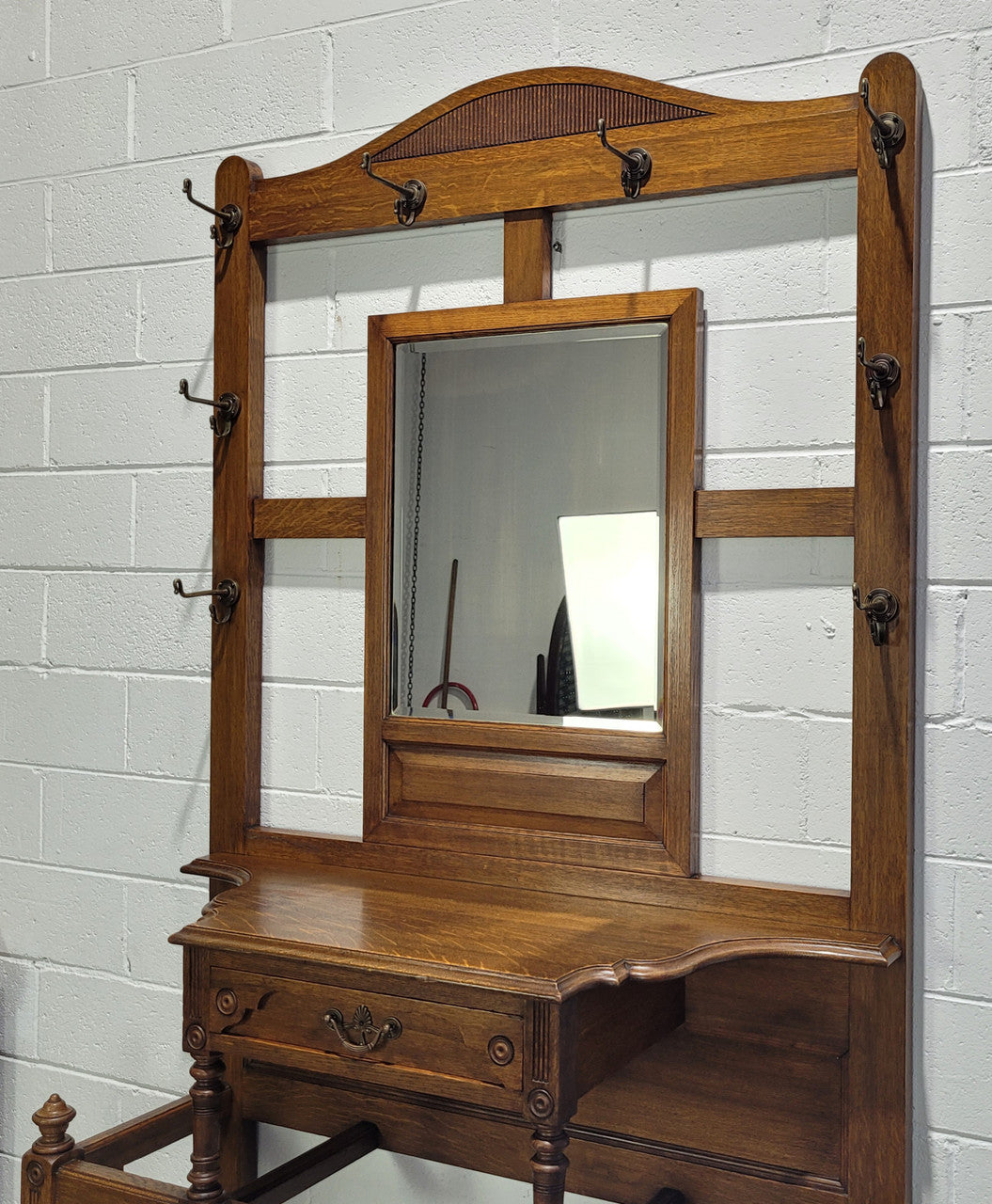 Impressive Oak hall stand of grand portions. Plenty of storage with a drawer, plenty of hooks and two sections for umbrealls/ walking sticks. It is in good original detailed condition.