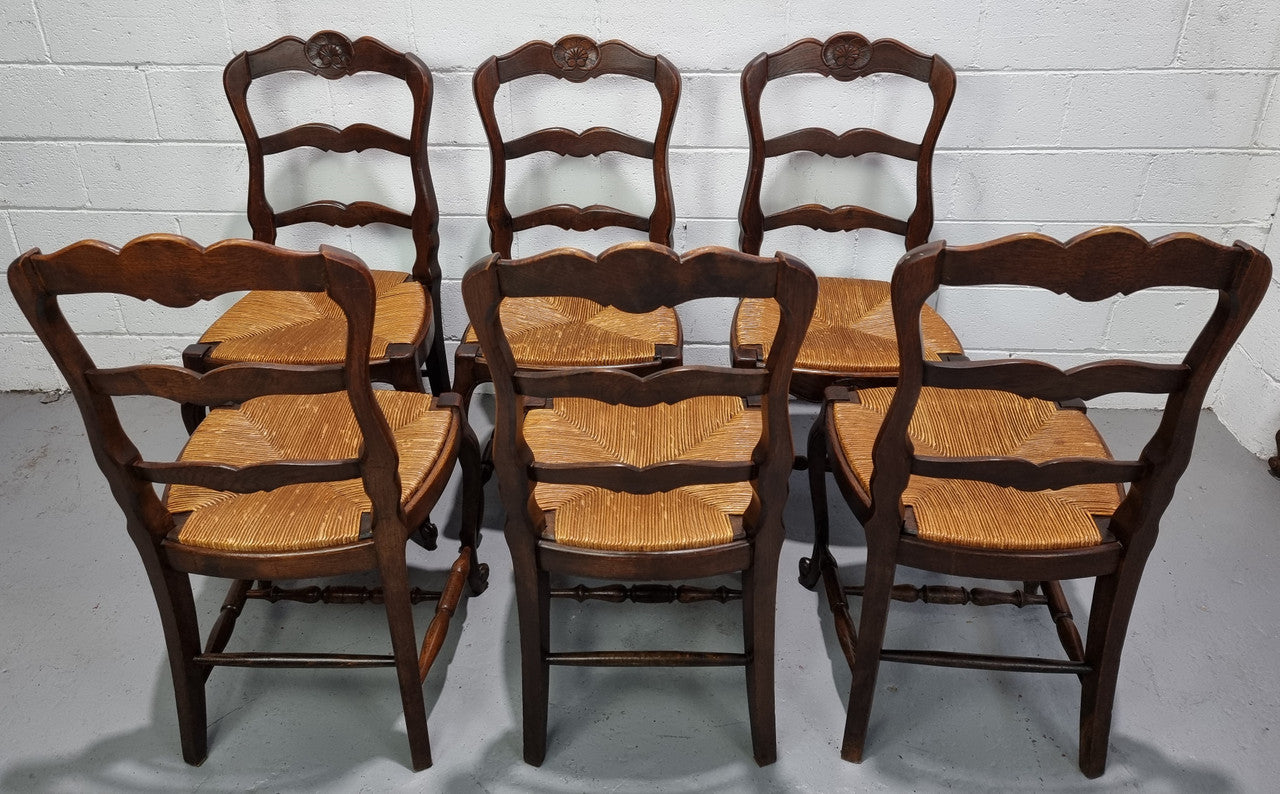 Set of six French dark Oak rush seat dining chairs with ladder back. They are in good detailed original condition and very comfortable to sit in.