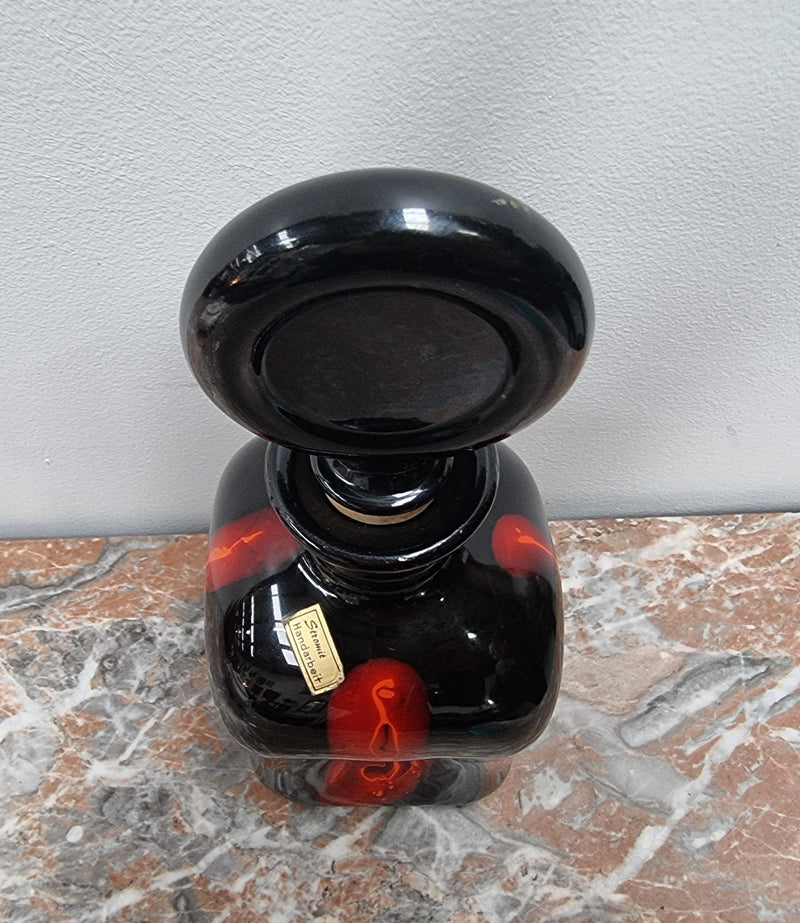 Vintage Designer glass carafe by “Stromit Handarbeit”.  Dark background with flashes of orange/red.