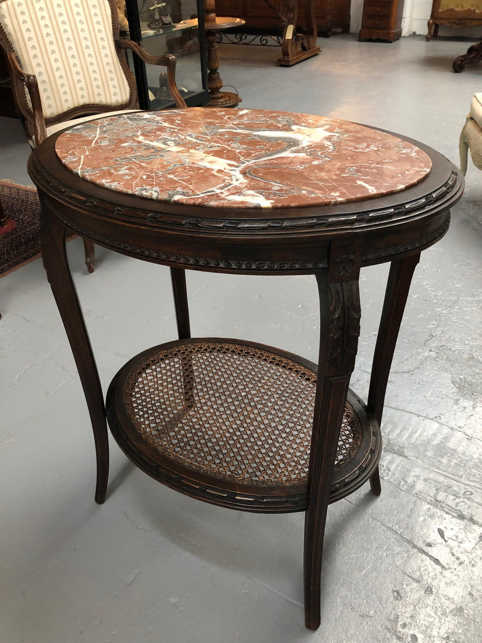 A charming 19th century French Louis XVI style fruitwood 2 tier oval side table. With marble top, cane base and carved detail on surrounds and legs.