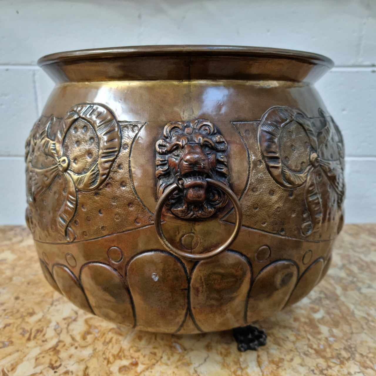 Antique large brass bronze coloured embossed Jardinière/planter with lovely details and lion heads for handles. It is in good original condition.