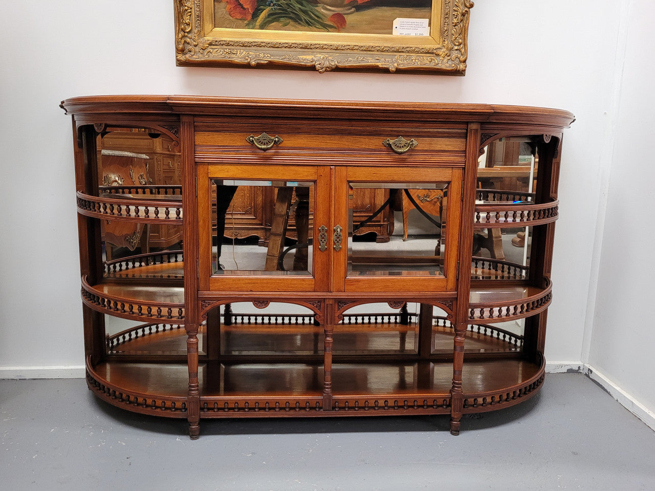 A high quality Antique Walnut sideboard featuring two mirrored doors, two drawers and five open shelf areas with mirror backing. It is in good original detailed condition.