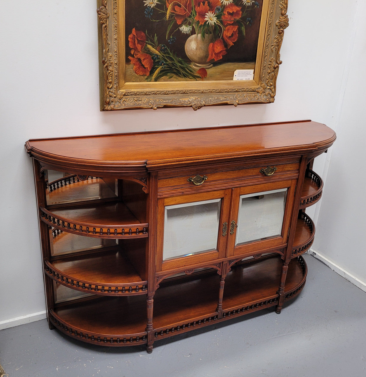 A high quality Antique Walnut sideboard featuring two mirrored doors, two drawers and five open shelf areas with mirror backing. It is in good original detailed condition.