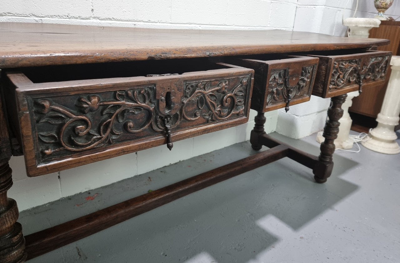 Rare and Charming 17th Century Spanish Walnut serving / side table. It has an incredible one piece walnut top with amazing character and colour. The base displays the original patina aswell as three drawers with carving and remnants of original locks. Superbly turned legs terminating on a stretcher base. Could be used as a large entrance console table, a side table or in a dining area as a serving table. In good original detailed condition especially considering its age.