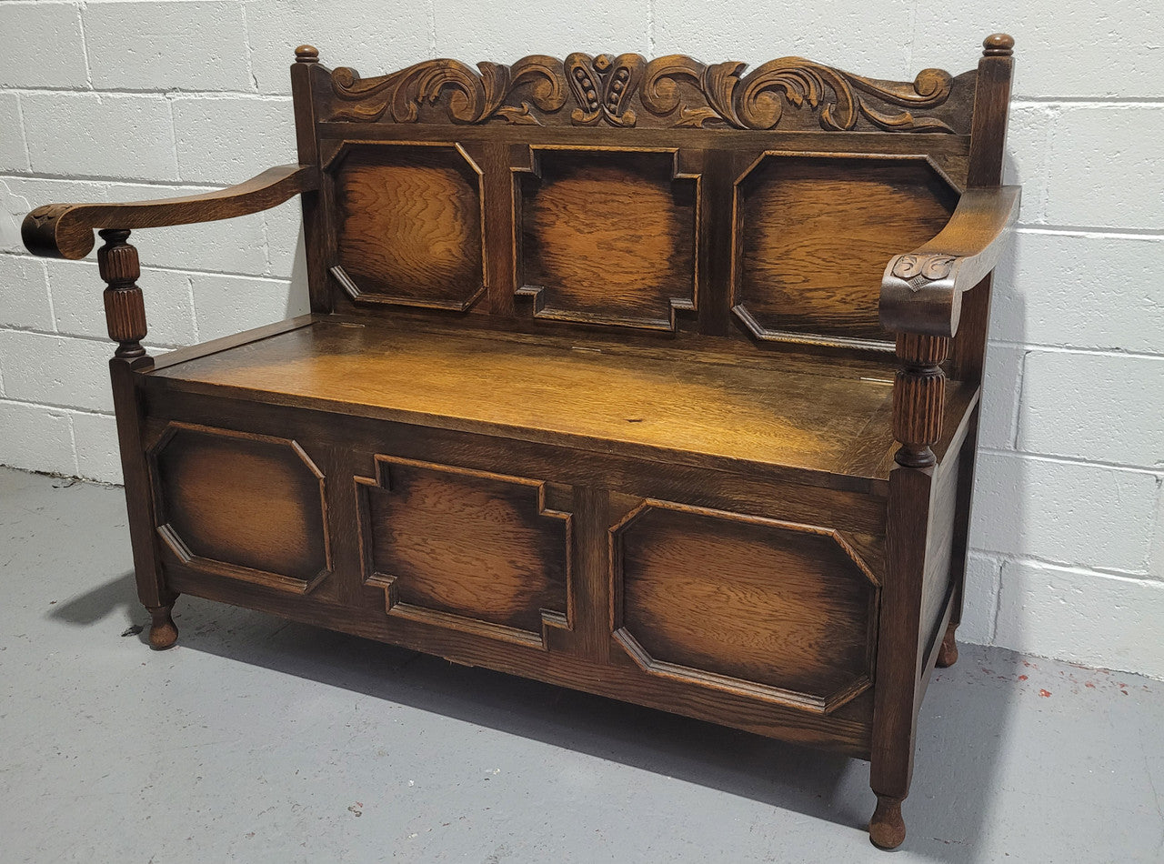 English Oak Tudor style hall seat with lift up top and a storage compartment underneath. It is in good original detailed condition with its original finish.