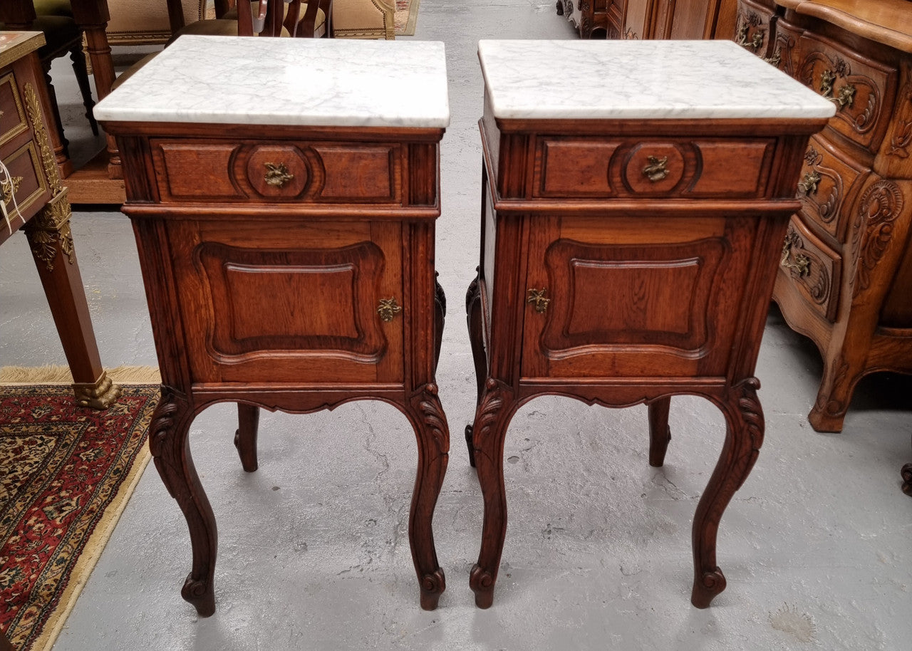 Elegant French Louis XV style pair of carved Oak white marble top bedsides. They are in good original condition and they have been detailed to a high standard. They have been sourced from France.