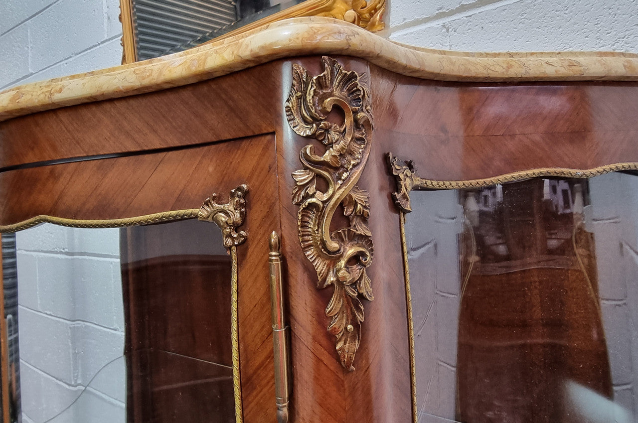Grand French Walnut Louis XV style marble top vitrine. It has two glass shelfs and one mirrored shelf at the bottom and added storage at bottom. It is in good original detailed condition.
