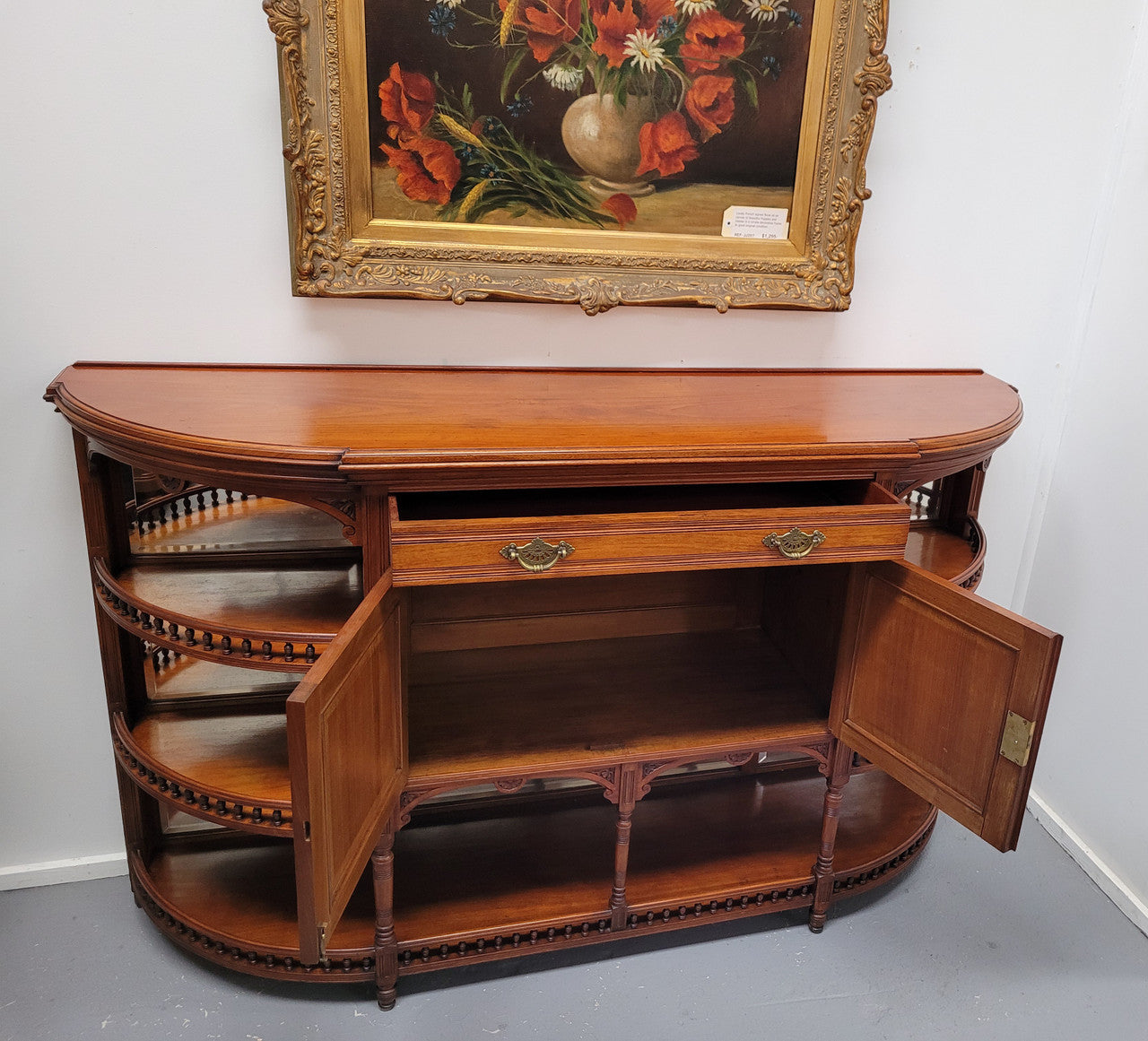 A high quality Antique Walnut sideboard featuring two mirrored doors, two drawers and five open shelf areas with mirror backing. It is in good original detailed condition.