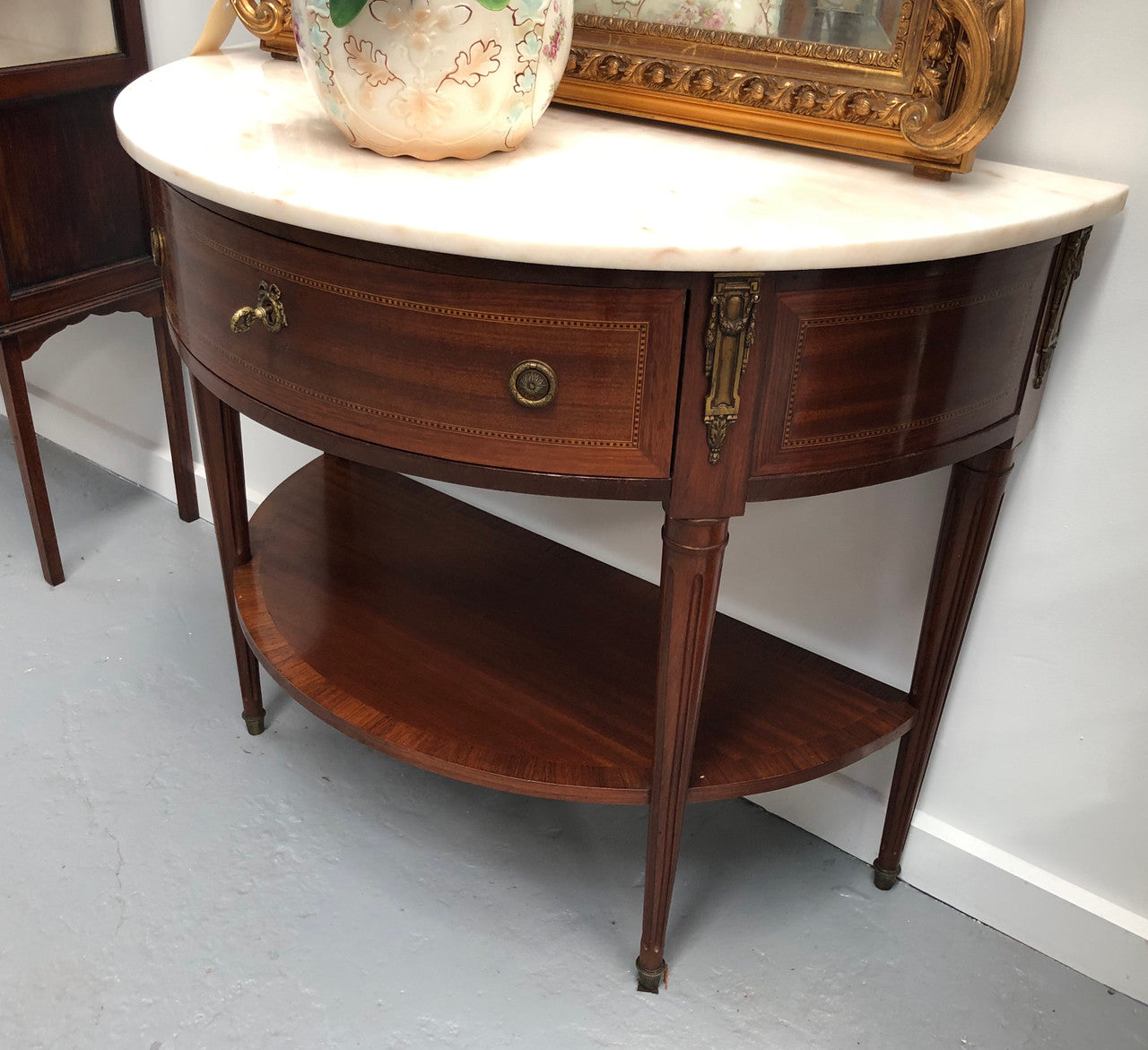 French marble top half round console table. It has beautiful marquetry inlay and ormolu mounts with a single drawer. In good original condition.