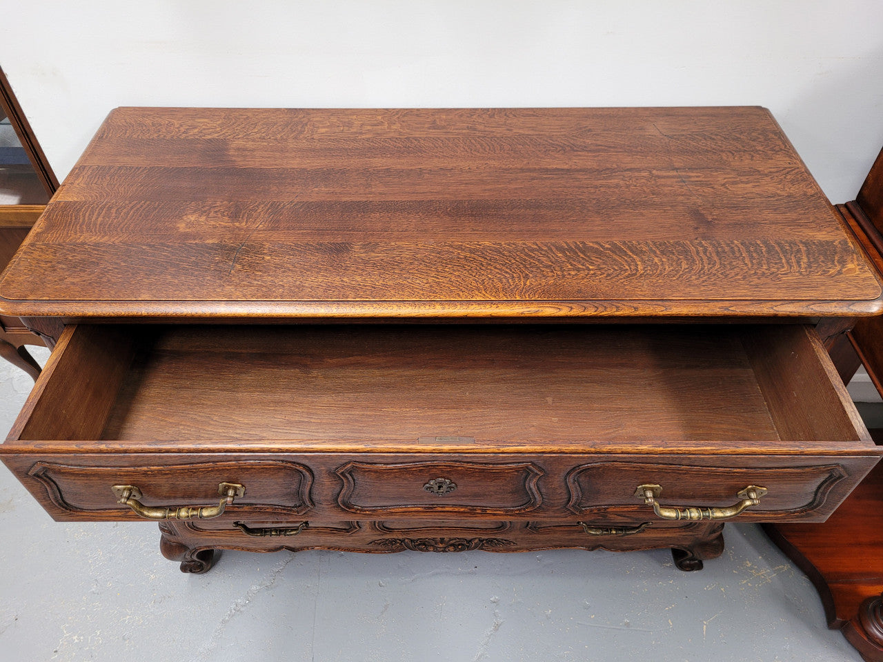 French Provincial Oak three drawer wooden top commode. It has elegant carvings and handles. It has been sourced from France and is in good original detailed condition.