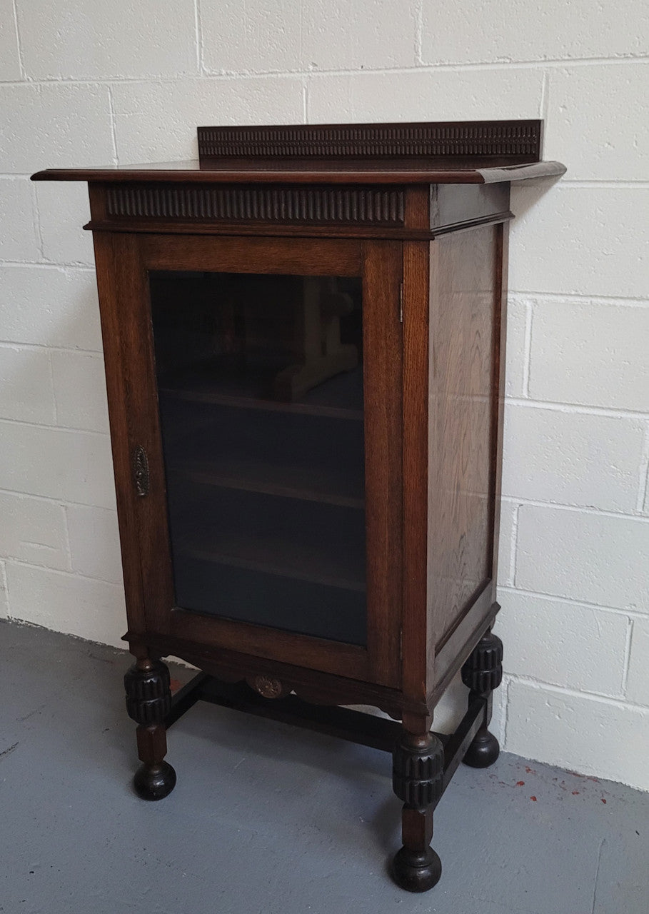 A very practical compact Oak Tudor style display cabinet with three fixed shelves. In good original detailed condition.