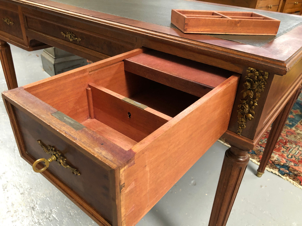 Lovely French Mahogany Louis XVI style leather top desk. With beautiful ormolu details and three drawers. There are also two slides on either side with tooled leather tops and in good original detailed condition.