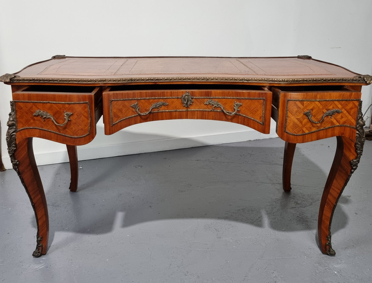 An impressive French kingwood and ormolu mounted bureau plat. It has a brown tooled leather writing surface, three decorated frieze drawers to the shaped apron with foliate swing handles and well cast figural mounts. Beautiful cabriole legs with decorative ormolu mounts and trims throughout. In good original detailed condition.