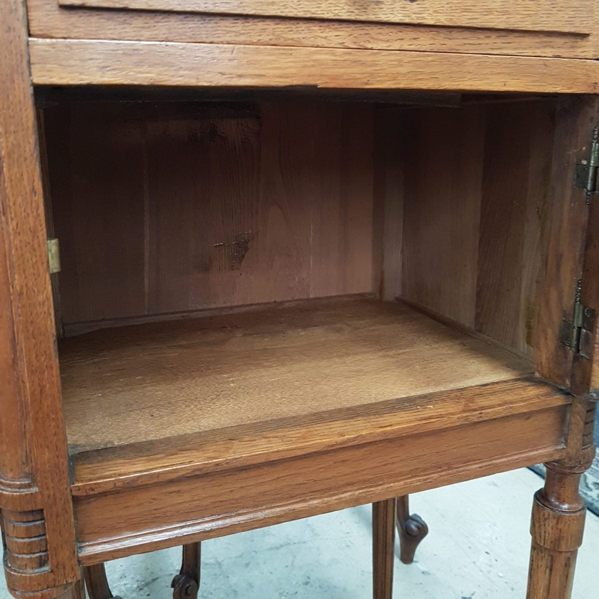 A French oak single bedside cabinet, with a marble inset top, finely carved detail, cupboard space and a drawer. In good original condition.