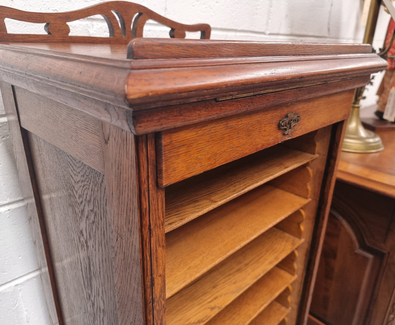 Antique Edwardian roll top Tambour file cabinet desk. This practical antique tambour front filing cabinet dates around 1900 in the Edwardian period and is constructed from Oak. This antique cabinet has an adjustable writing slope, above a tambour front with key and working lock. It has been sourced locally and is in good original detailed condition.