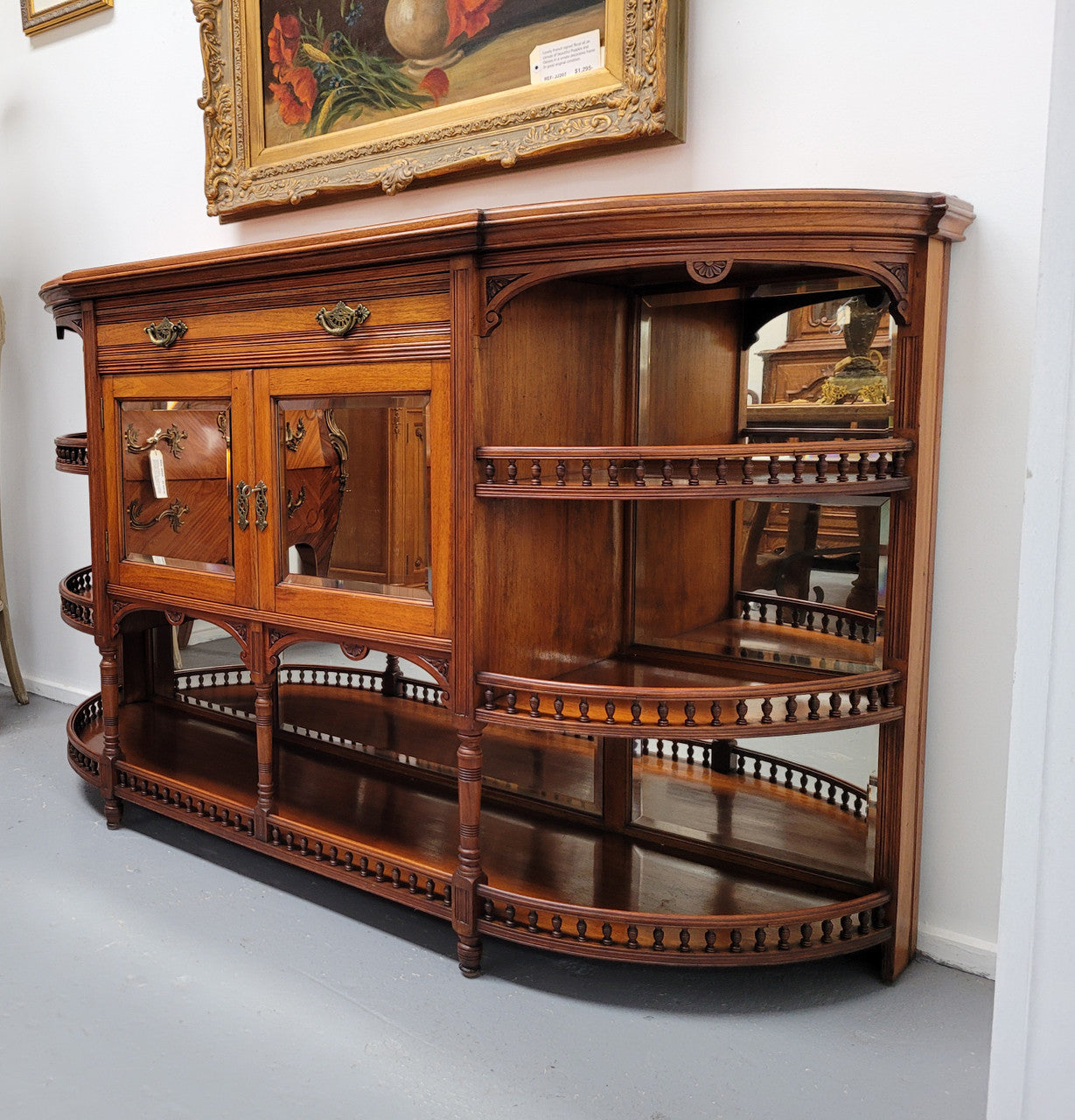 A high quality Antique Walnut sideboard featuring two mirrored doors, two drawers and five open shelf areas with mirror backing. It is in good original detailed condition.