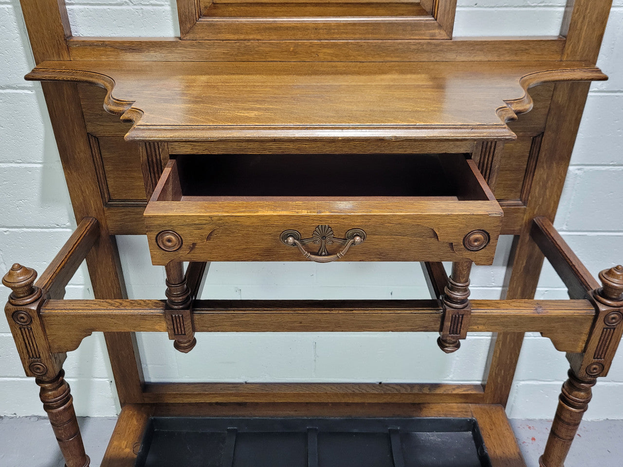 Impressive Oak hall stand of grand portions. Plenty of storage with a drawer, plenty of hooks and two sections for umbrealls/ walking sticks. It is in good original detailed condition.