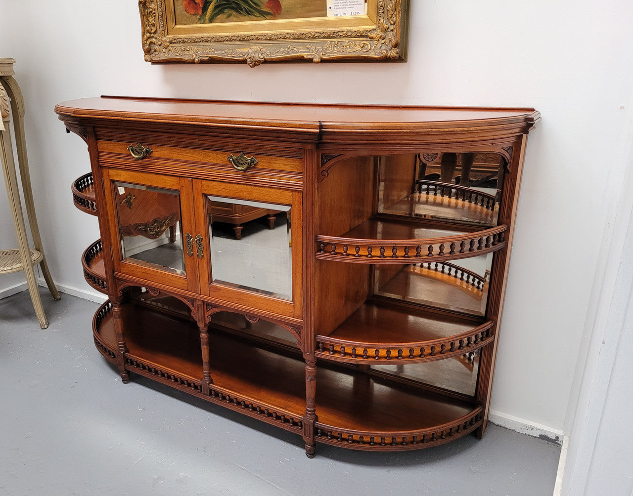 A high quality Antique Walnut sideboard featuring two mirrored doors, two drawers and five open shelf areas with mirror backing. It is in good original detailed condition.