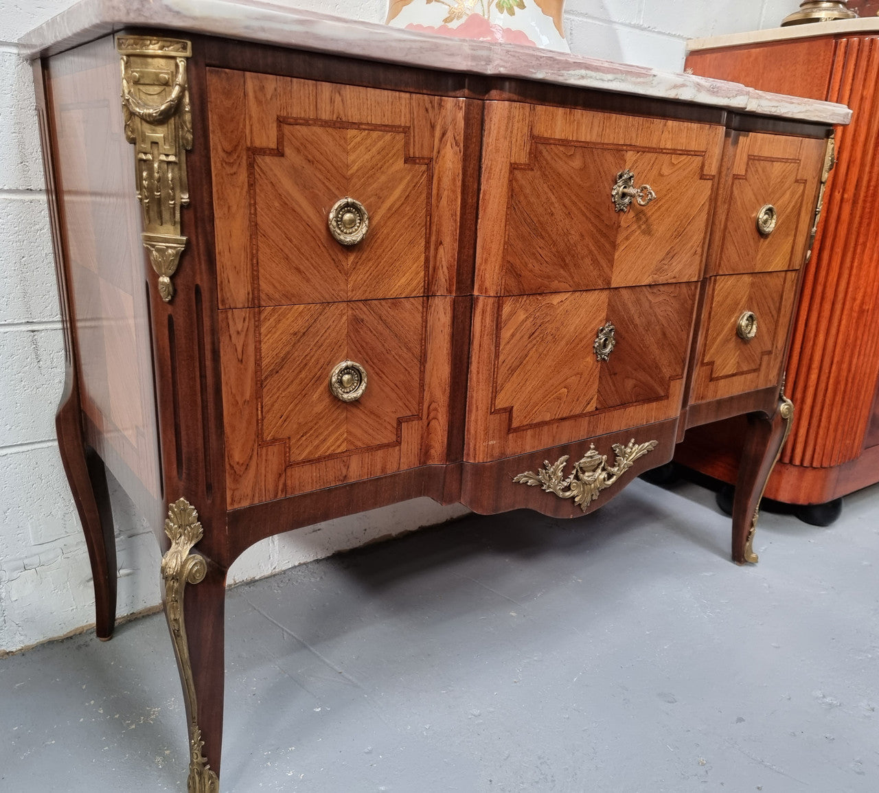 A stunning French transitional Louis XV and Louis XVI style commode. It has beautiful walnut inlay and a fabulous marble top. Comes with two drawers and fitted with gilt brass mounts. it is In very good original condition.