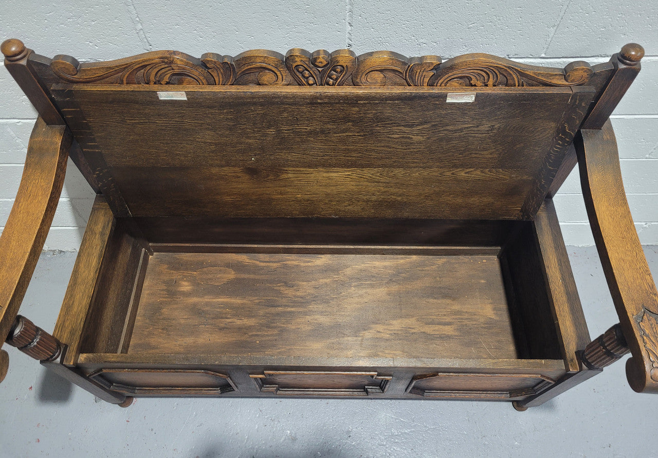 English Oak Tudor style hall seat with lift up top and a storage compartment underneath. It is in good original detailed condition with its original finish.