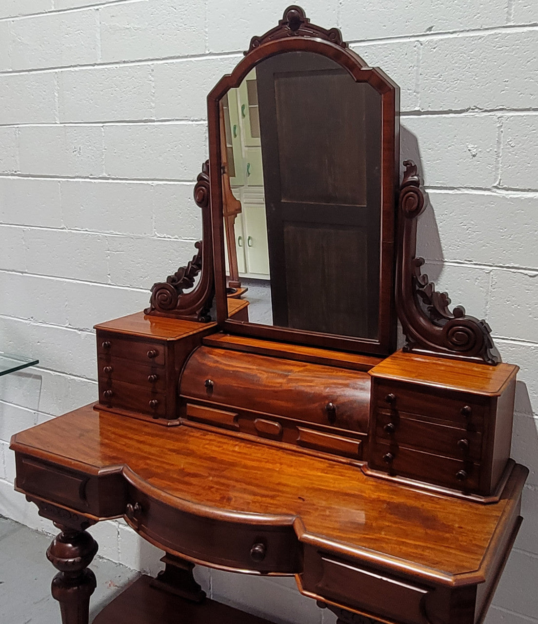 Beautiful Flame Mahogany Victorian duchess dressing table. Circa 1880 in date. It has a serpentine front outline and has an adjustable swing frame mirror. It is fitted with a central roll up storage section and then has three small drawers to either side, aswell as a central drawer in the middle of the serpentine front. It is in good original condition.